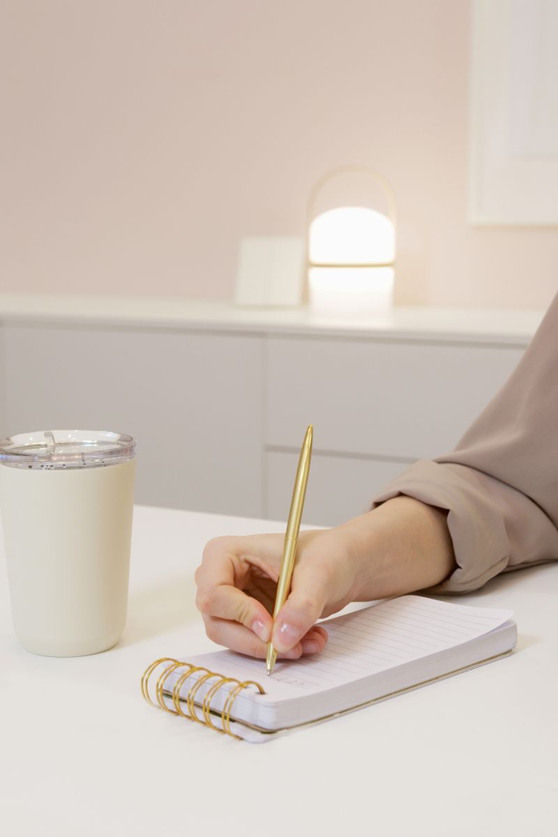 A woman planning her day with a notebook and coffee at a bright desk